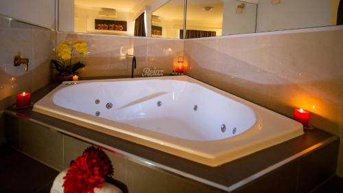 昆比恩Hamilton's Queanbeyan Motel的一个带蜡烛的浴室内的一个大型白色浴缸