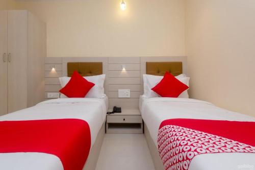 孟买Hotel Embassy Suites - Bandra Kurla Complex - BKC Mumbai的宿舍间内的两张床,配有红色枕头