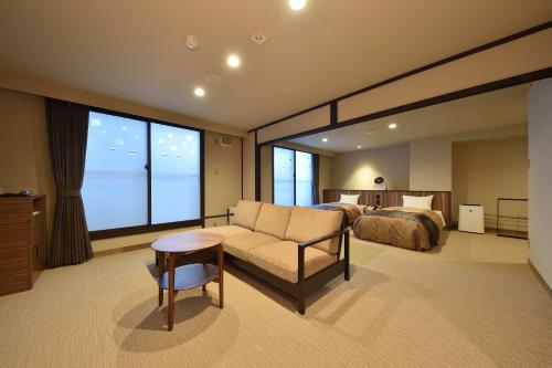 美瑛町aonobi yuyu的酒店客房配有床、沙发和桌子。