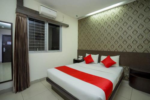 沙马林达Hotel Grand Kartika的一间卧室配有一张带红色枕头的床和一扇窗户