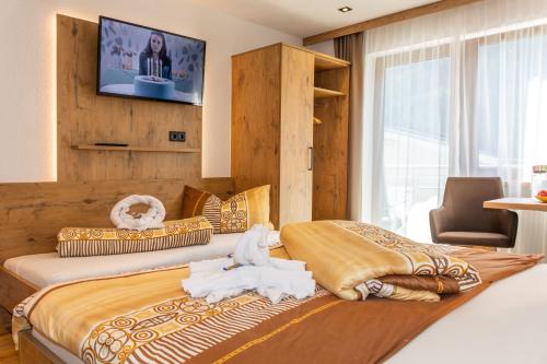 卡普尔Garni Samnaun的卧室配有两张床,墙上配有电视。