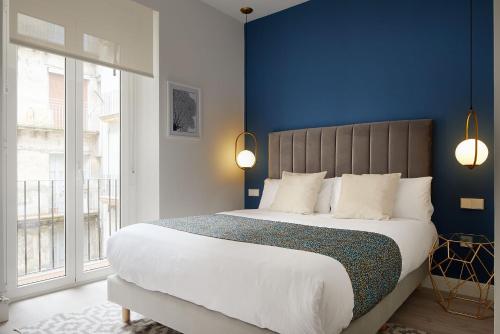 圣塞瓦斯蒂安ARRASATE SUITE Stylish, Super Central and New.的一间卧室设有一张蓝色墙壁的大床