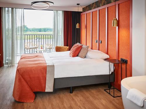 阿尔森De Maasparel Nextdoor Suites的一间带大床的卧室和一个阳台