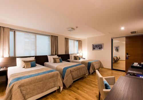 科尔多瓦Caseros 248 Hotel的酒店客房配有两张床和一张书桌