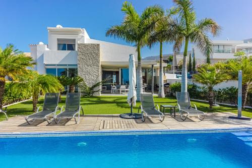 阿德耶Villa Eleonora, Luxury Villa with Heated Pool Ocean View in Adeje, Tenerife的房屋旁的游泳池配有椅子和遮阳伞