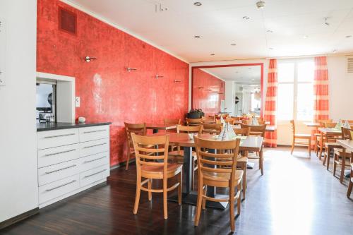 Niederuzwilhotel löwen的一间拥有红色墙壁和桌椅的用餐室