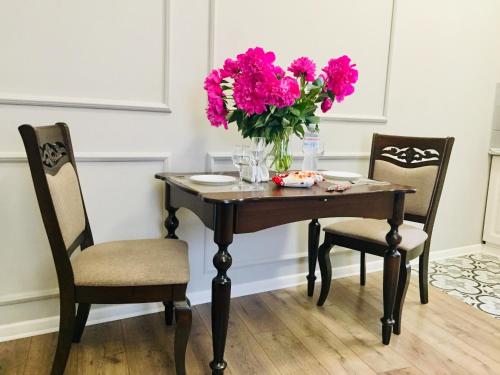 切尔诺夫策Апартаменти Кобилянська 9的一张桌子,两把椅子和一瓶粉红色的花