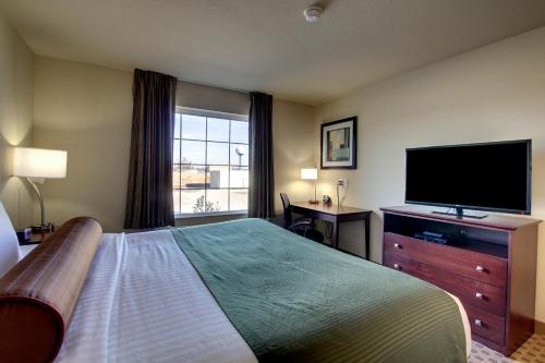 HarveyCobblestone Inn & Suites - Harvey的配有一张床和一台平面电视的酒店客房
