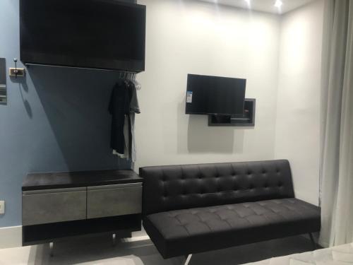 里约热内卢Ipanema Prudente Studio的客厅配有黑色真皮沙发和电视