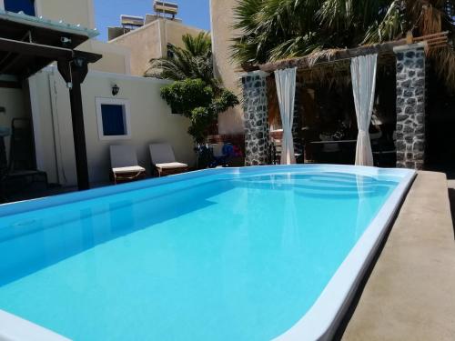 佩里萨5bedroom villa in perissa beach的一个带两把椅子的庭院里的一个大型蓝色游泳池