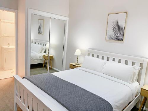 阿米代尔Bright 3-bedroom apartment - Central Armidale的卧室配有一张白色大床和镜子