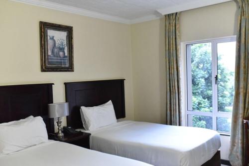 彼得马里茨堡Regal Inn PMBurg的酒店客房设有两张床和窗户。