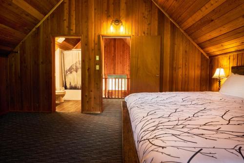 坎莫尔班夫门山度假酒店的木制客房内的一间卧室配有一张大床