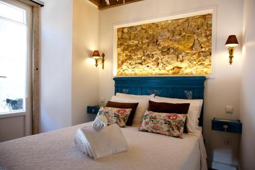 塞图巴尔Cafofos da Zeta的一间卧室配有一张床铺,上面有石墙