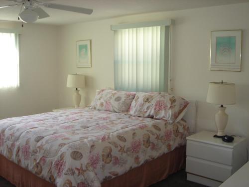 Point O'RocksIsland House Beach Resort 13的一间卧室配有一张床、两盏灯和两扇窗户。