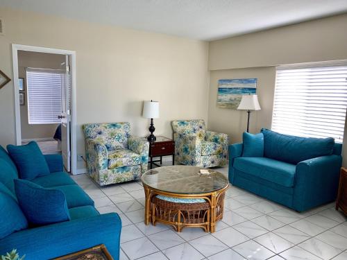 Point O'RocksIsland House Beach Resort 12N的客厅配有蓝色的沙发、桌子和椅子