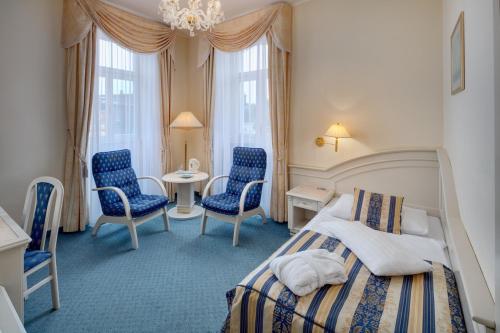 玛丽亚温泉Ensana Hotel Pacifik的一间卧室配有一张床、两把椅子和一张桌子