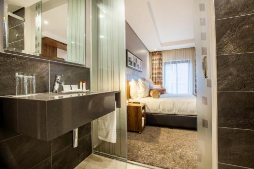 约翰内斯堡City Lodge Newtown, Johannesburg的一间带水槽的浴室和一张位于客房内的床