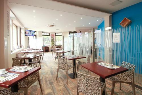 马尔芒德Hôtel La Couronne的餐厅设有木桌和椅子,拥有蓝色的墙壁