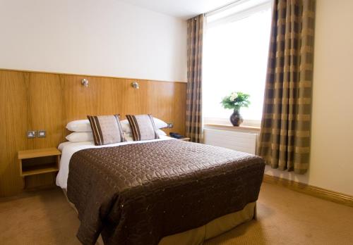 都柏林布鲁姆斯酒店的一间卧室设有一张大床和窗户