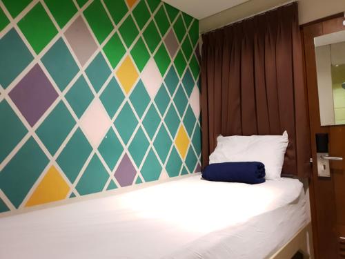 万隆苏布瓦旅馆的一间卧室设有一张床和色彩缤纷的墙壁