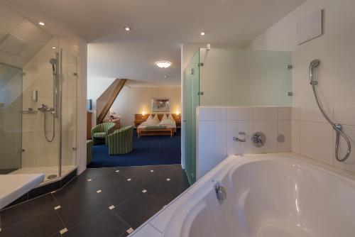 贡滕Parkhotel Gunten – Beach & Spa的带浴缸的大浴室和卧室
