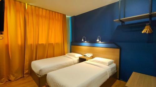 仙本那Uptown Hotel的蓝色和橙色墙壁的客房内的两张床