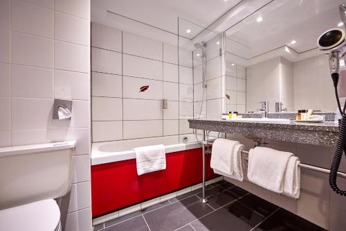 巴特科尔格鲁布施灵格斯霍夫酒店的浴室配有红色和白色的盥洗盆和浴缸。