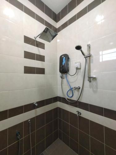 珍南海滩Ku's Roomstay的浴室铺有棕色和白色瓷砖,设有淋浴。