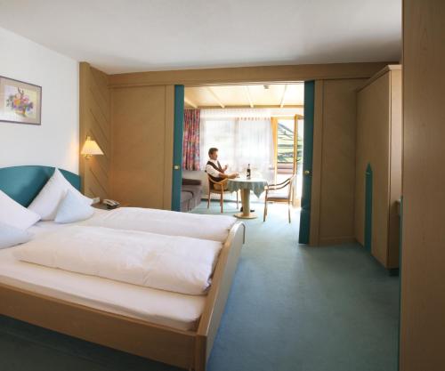 瑙德斯贝格布里克酒店的卧室配有一张床,而人坐在桌子上
