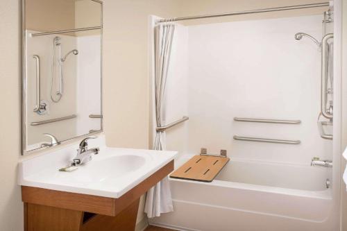 罗利WoodSpring Suites Raleigh Northeast Wake Forest的一间带水槽、浴缸和淋浴的浴室