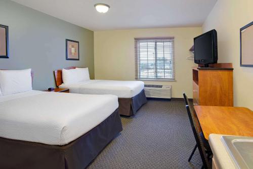罗利WoodSpring Suites Raleigh Northeast Wake Forest的酒店客房设有两张床和一台平面电视。