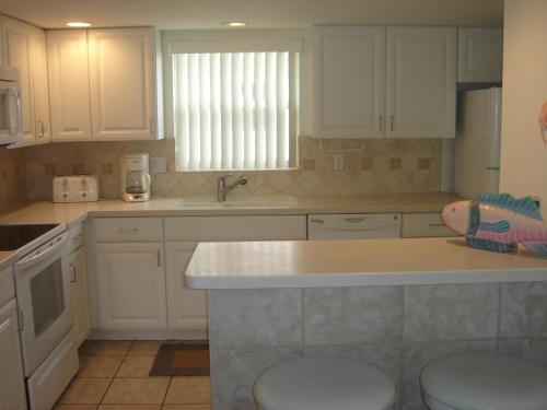 Point O'RocksIsland House Beach Resort 23的厨房配有白色橱柜和台面