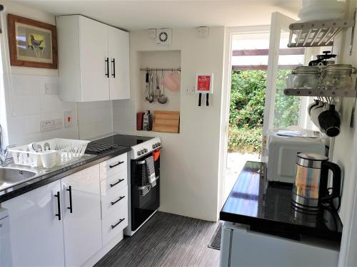 MoretonPrimrose Cottage的厨房配有白色橱柜和黑色台面