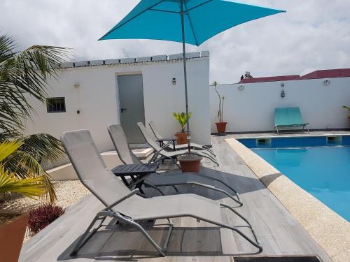 PoponguineAfrican Jaja villa Piscine-Climatisation的游泳池旁带椅子和遮阳伞的天井