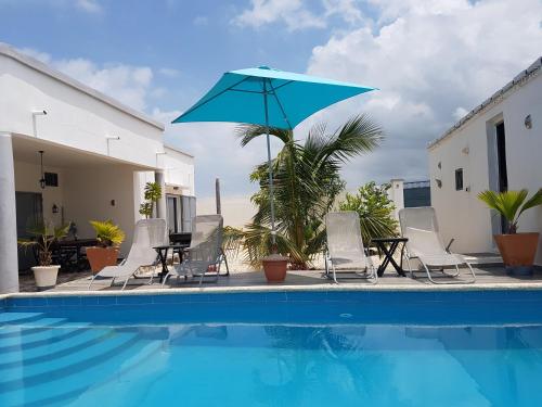 PoponguineVilla JAJA Piscine-Climatisation的一个带椅子和蓝伞的游泳池