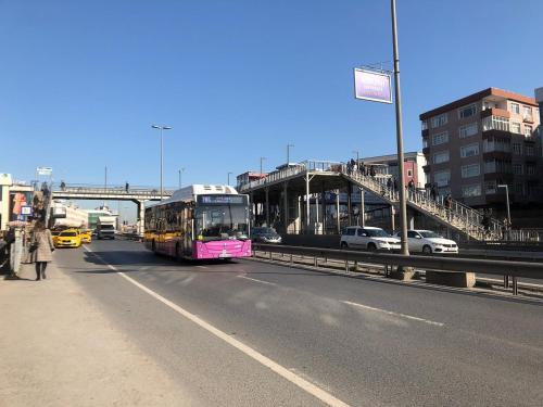 伊斯坦布尔Istanbul Fair Hotel的一辆粉红色的巴士沿着一条城市街道行驶