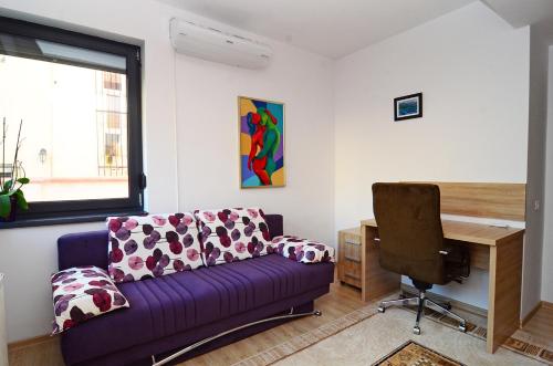 布加勒斯特Luxury apartment by the park / Arch of Triumph的客厅配有紫色沙发和书桌