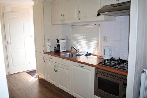 羊角村Resort Venetie Chalet nr.42的厨房配有白色橱柜、水槽和炉灶。