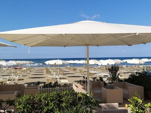 卡斯蒂里昂纳·德拉佩Aqua Boutique Hotel的海滩上设有白色的遮阳伞和椅子,还有大海