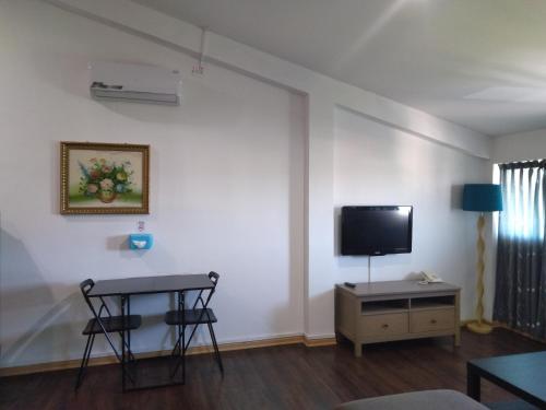 斯里巴加湾市昆普勒克吉拿27号酒店的客厅配有桌子,墙上配有电视