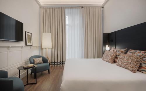 马拉加TOC Hostel Malaga的酒店客房带一张大床和一把椅子