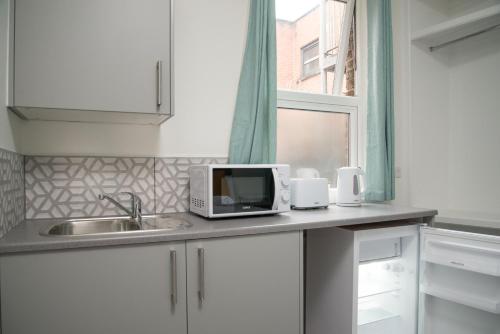 贝肯翰姆TLK Apartments & Hotel - Beckenham High Street的厨房柜台配有微波炉和水槽