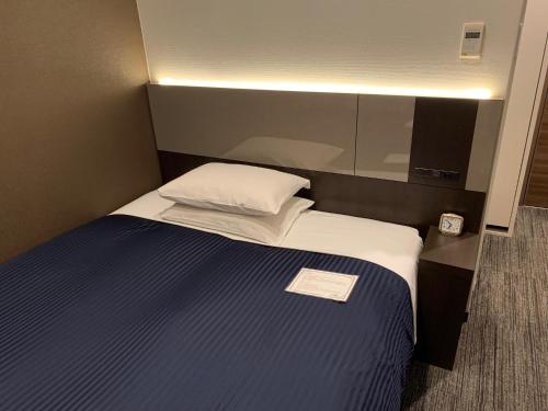 东京御茶水酒店的一间小卧室,配有一张带白色枕头的床