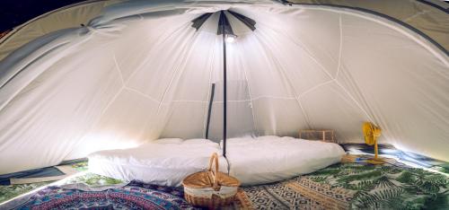 桃园市晃晃印地安帐棚露营区的配有床和遮阳伞的白色帐篷