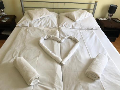 锡盖特堡Hotel Oroszlán Szigetvár的白色的床,带有心形的毛巾
