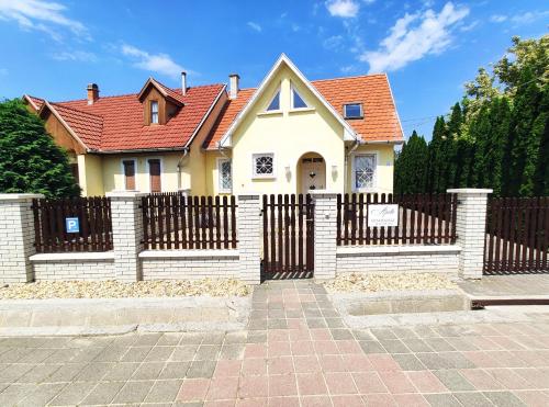 博加奇Apollo Vendégház的一座带围栏和红色屋顶的房子