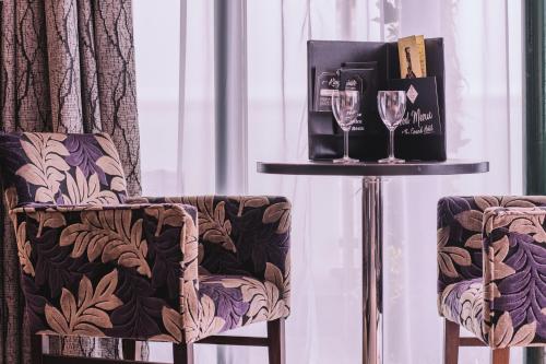 斯旺西格兰德酒店的两把椅子和一张桌子及葡萄酒杯