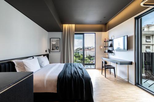 雅典The Modernist Athens的酒店客房设有一张床、一张书桌和一个阳台。