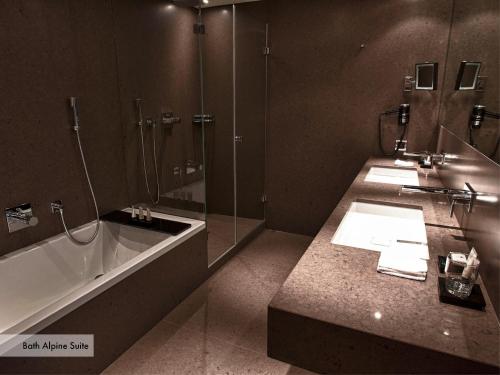 达沃斯达沃斯格里希尔酒店的浴室配有2个盥洗盆、浴缸和淋浴。